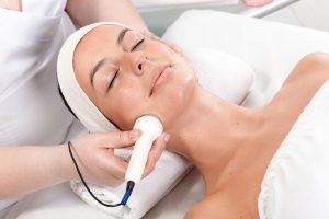 Young woman laying eyes closed, receiving facial beauty treatment in beauty saloon.